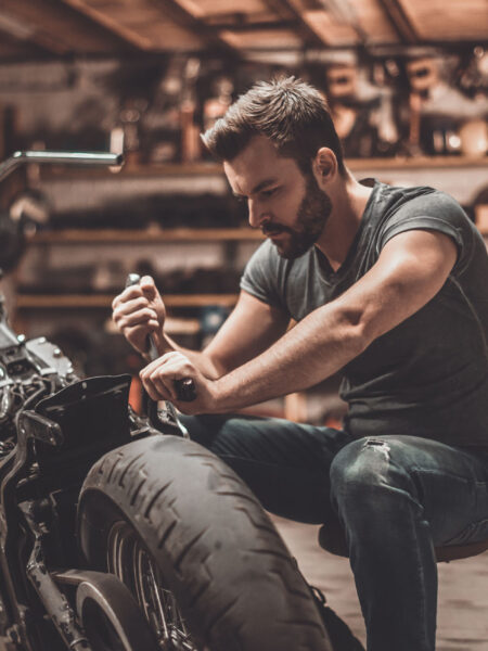 This bike will be perfect. Confident young man repairing motorcycle in repair shop